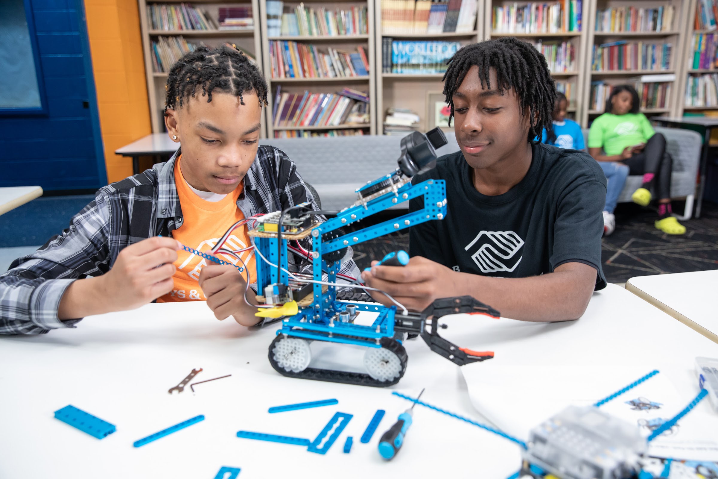 Two teens building a robotic arm together in a Club STEM program